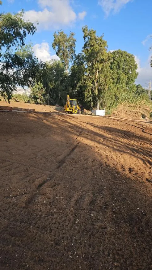 מחפרון בעבודות עפר ויישור קרקע בשטח פתוח לפני שתילה מחפרון בעבודות עפר ויישור קרקע בשטח פתוח לפני שתילה