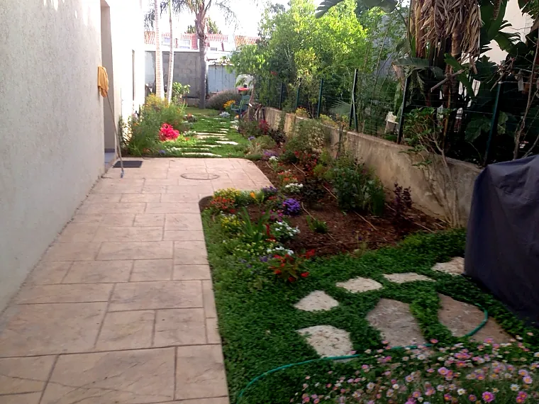 garden-path-stepping-stones-lawn שביל מרוצף ואבני מדרך בתוך כיסוי ירוק וערוגות פרחים בגינה פרטית